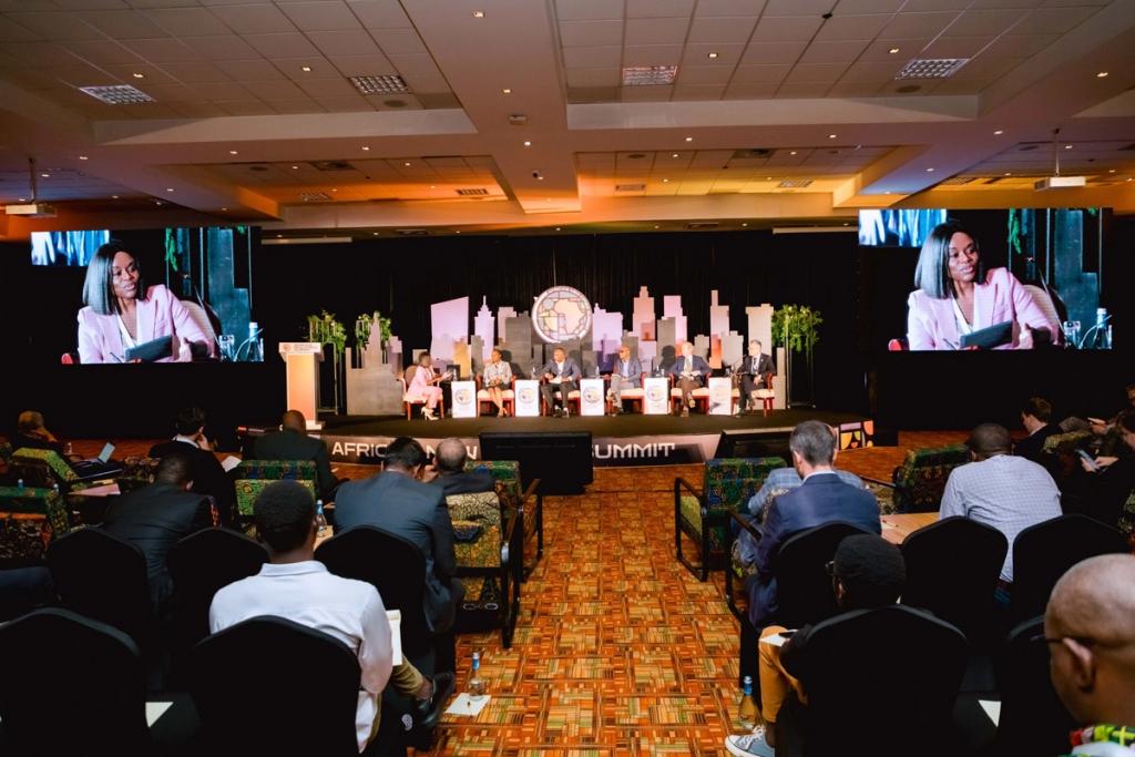 CCI Africa Lead Mwanda Phiri on big screens moderating a panel at Africa's New Cities Summit in Kigali