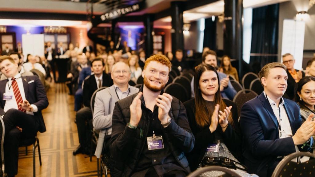 Smiling attendees with name badges applauding in the audience at the Free Cities Conference in Prague