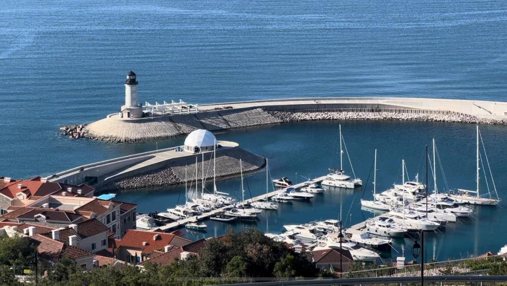 Marina with sailing yachts, breakwater and white lighthouse at the Zuzalu pop-up city site in Montenegro