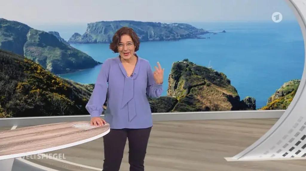 ARD Weltspiegel presenter in the studio in front of a backdrop of Sark's cliffs and coastline