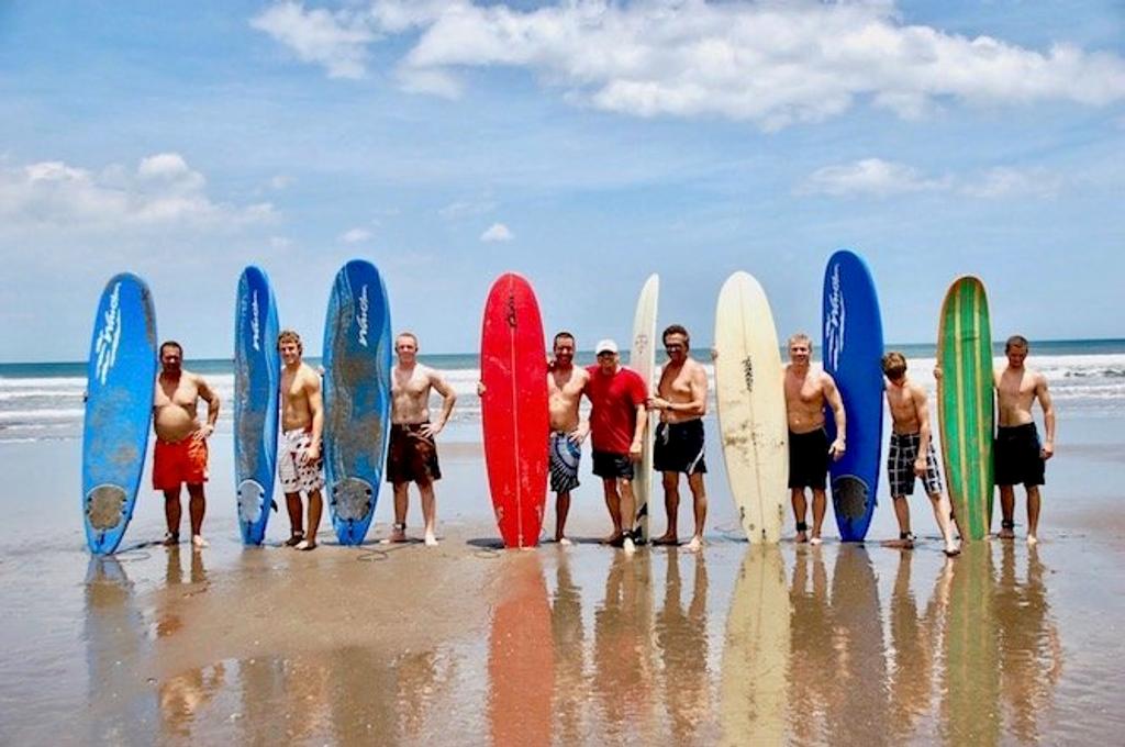 Group of surfers standing with their boards on the beach at Gran Pacifica, Nicaragua