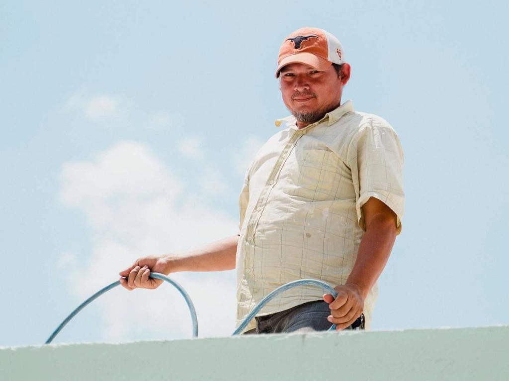 Maintenance worker holding a hose on a rooftop in Ciudad Morazán, Honduras