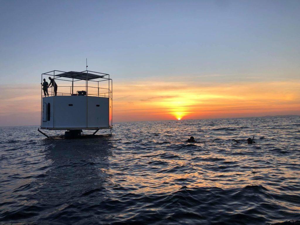 Seastead unifamiliar de Chad Elwartowski y Nadia en aguas de Tailandia al atardecer, con dos personas en la cubierta