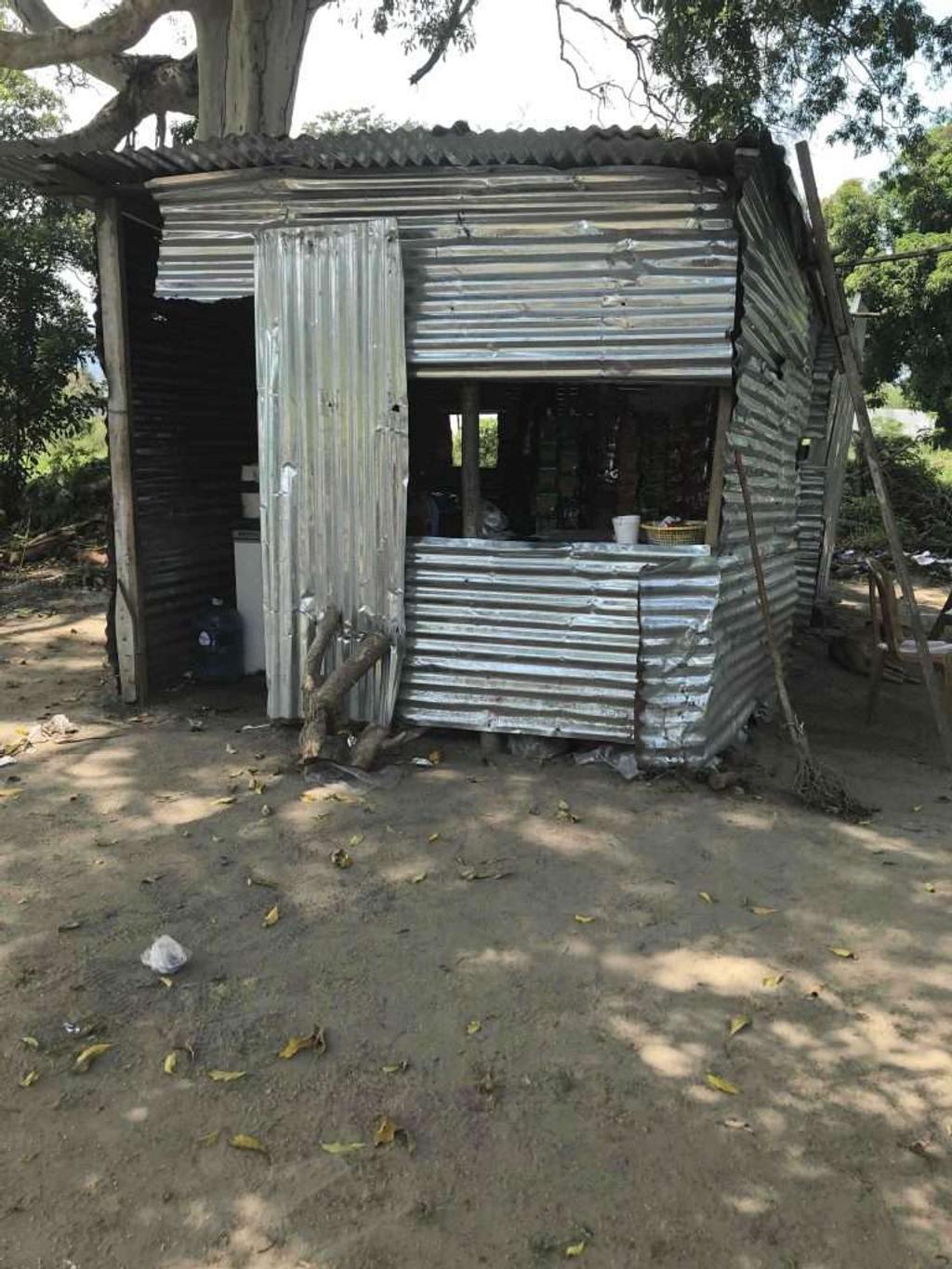 Small corrugated metal shack under a tree, Rosa's first snack stand in Ciudad Morazán