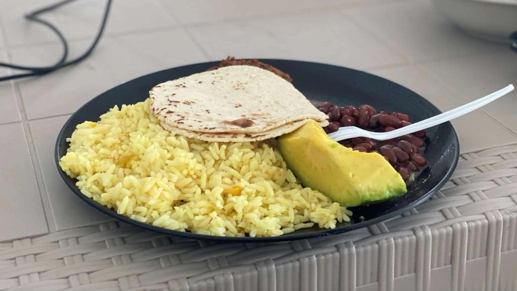 Honduran lunch plate with yellow rice, red beans, avocado and tortillas served at Rosa's restaurant