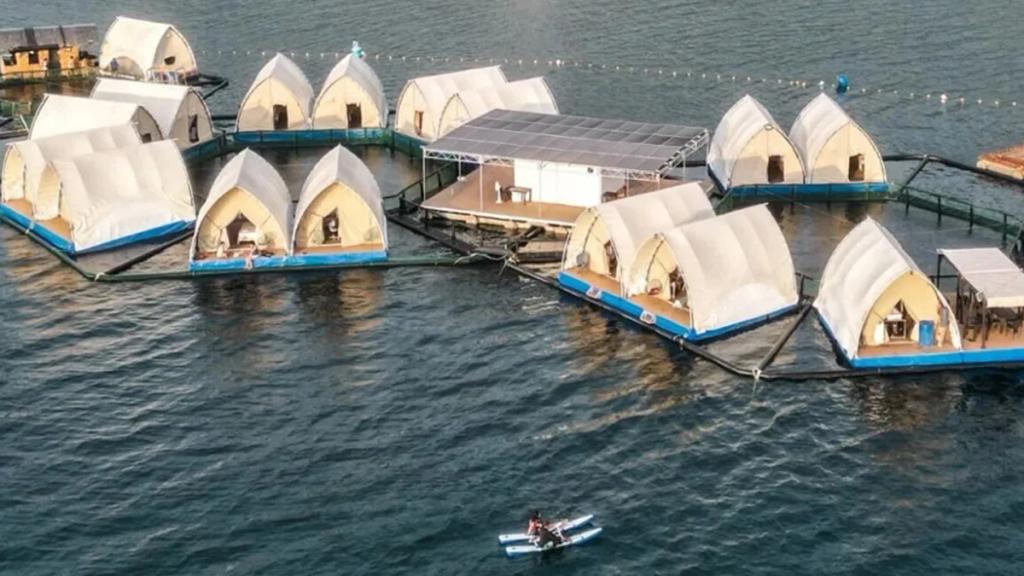 Aerial view of ArkPad's floating reef resort in the Philippines, tented units linked around a solar platform