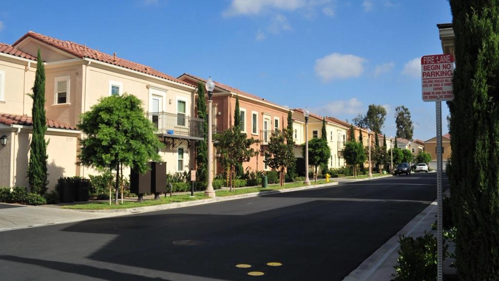 Mediterranean-style apartment homes with red tile roofs along a tree-lined street in Irvine, California