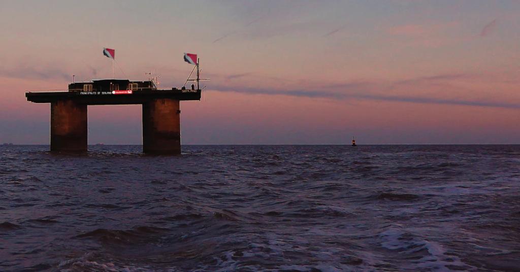 Plataforma oxidada del Principado de Sealand sobre dos torres en el mar, con sus banderas, al atardecer