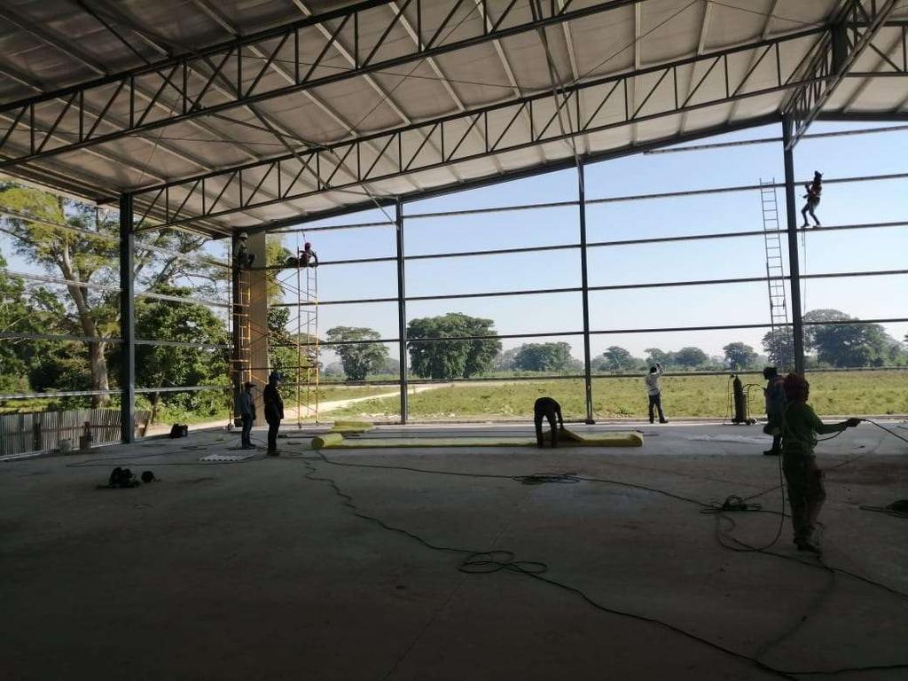 Workers on scaffolding building the steel frame of the first warehouse in ZEDE Ciudad Morazán