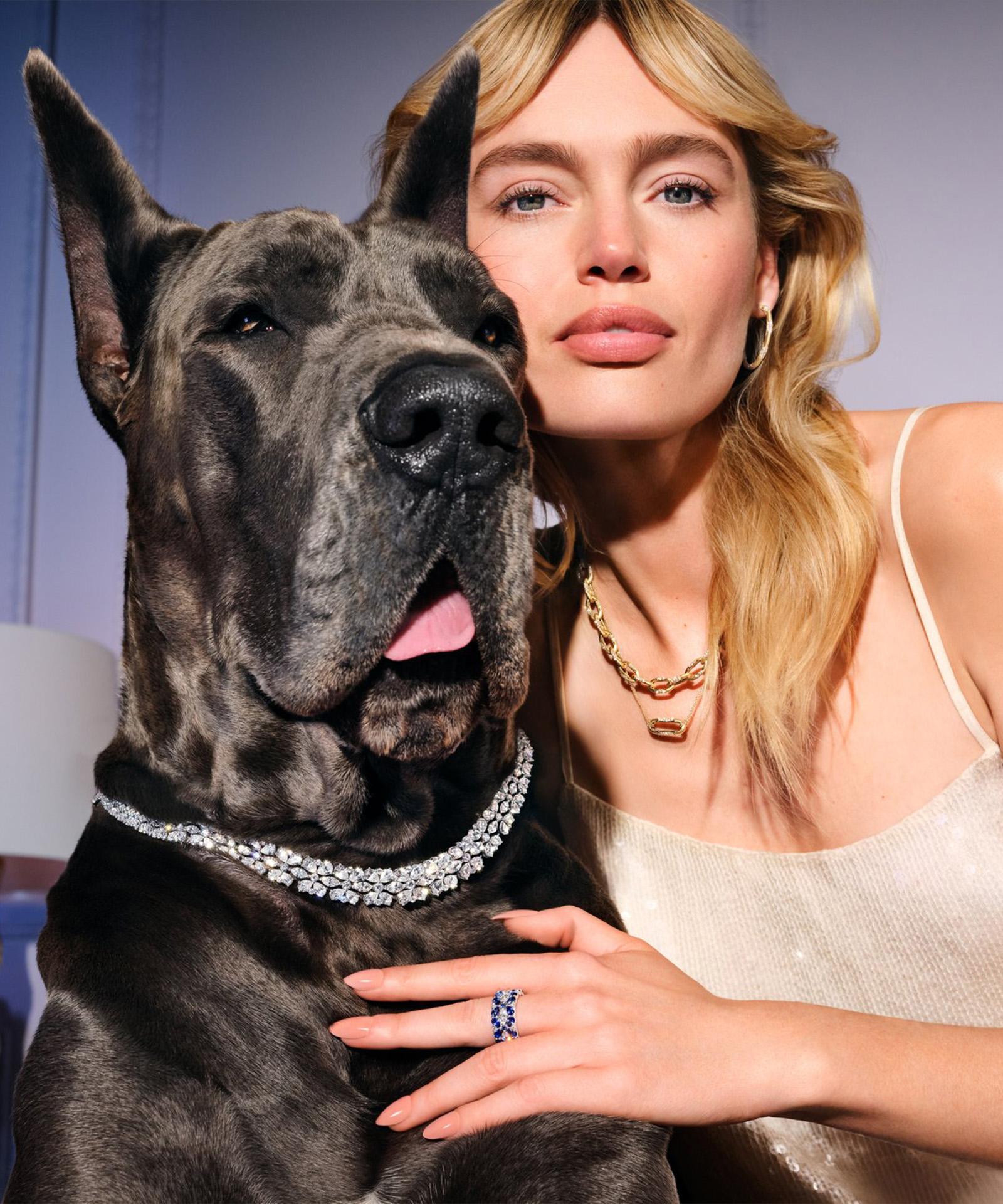 Blond woman wearing rings and necklace against blue velvet background