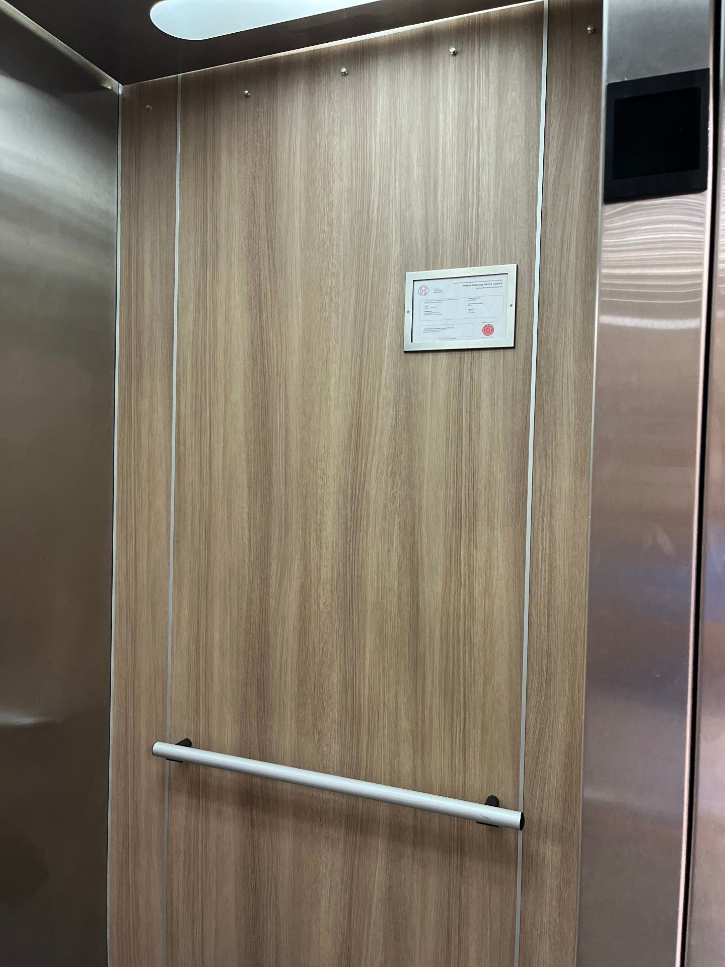 Elevator cab wall wrapped in warm wood grain vinyl film