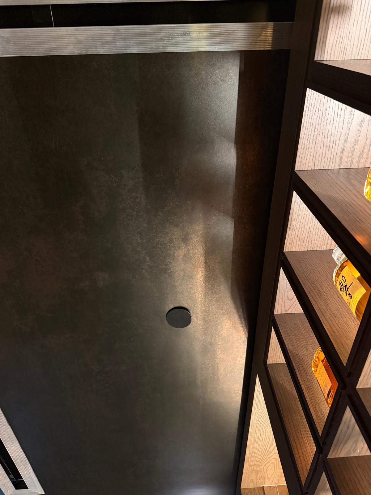 Close-up of dark bronze ceiling finish beside wood shelving