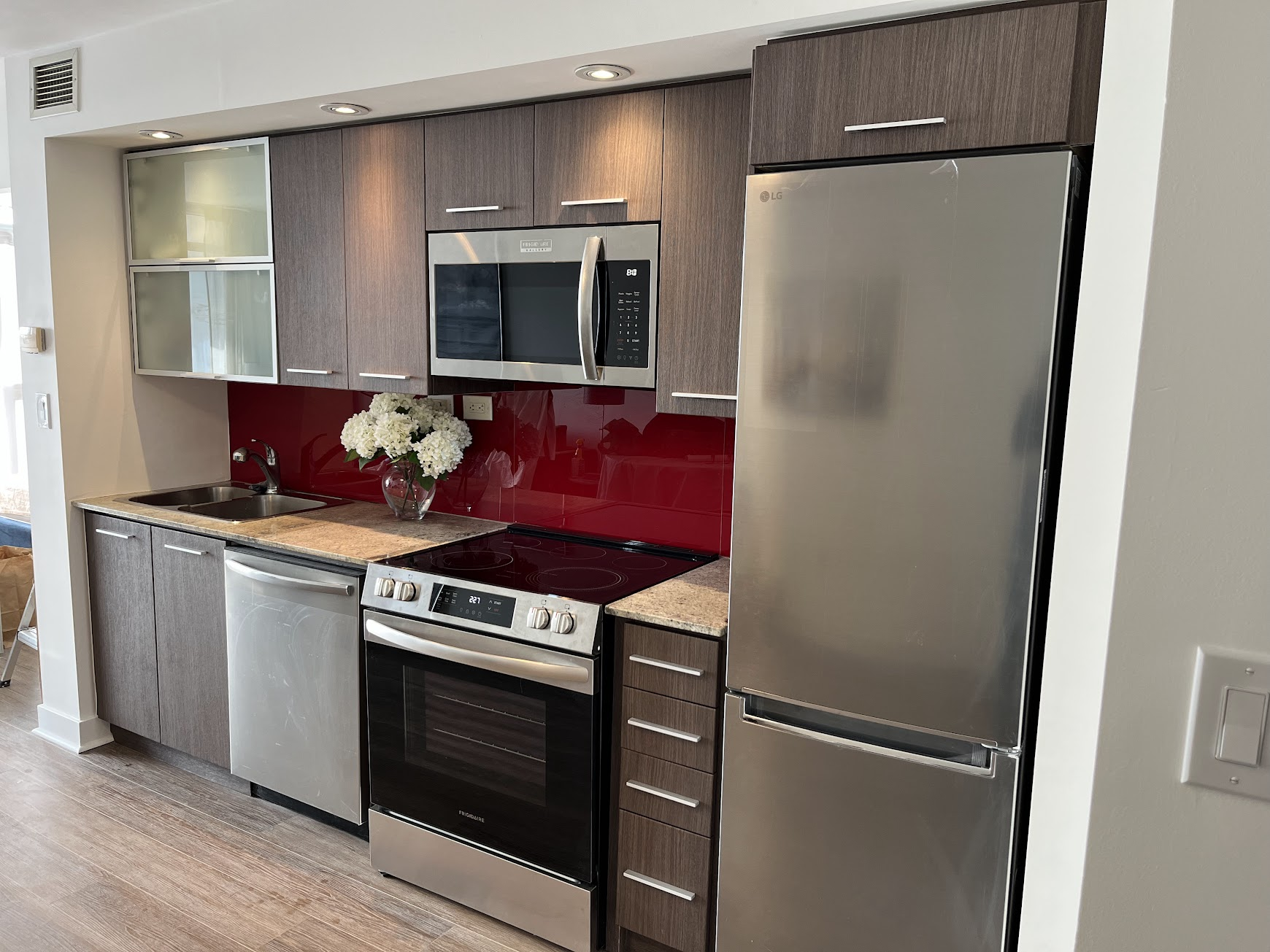 Dark woodgrain vinyl-wrapped condo kitchen cabinets