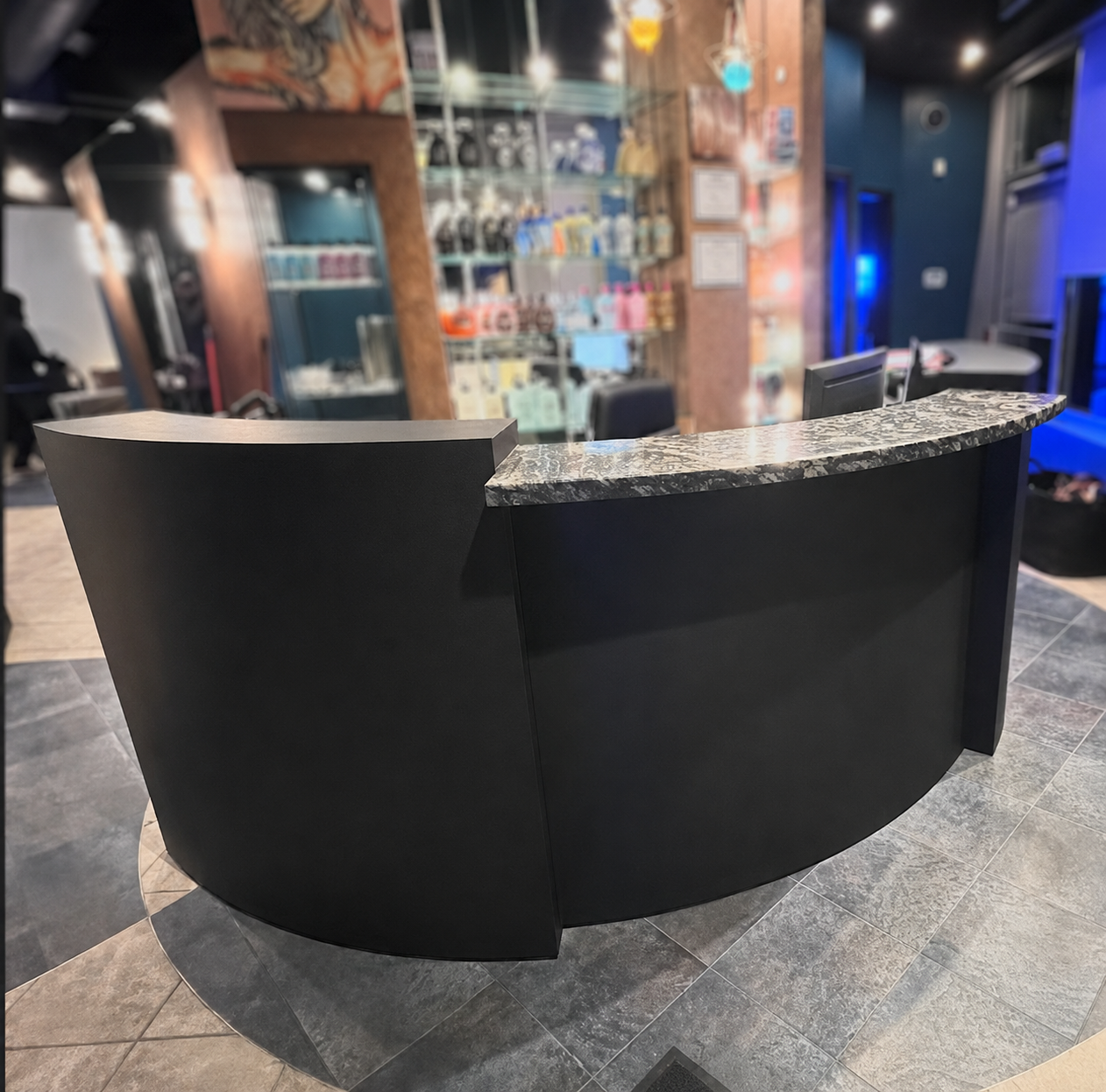 Curved black salon reception desk with marble countertop wrap
