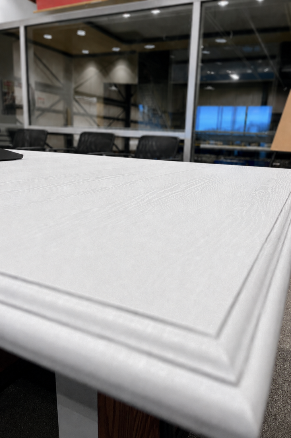 Close-up of a reception desk finished in premium white woodgrain architectural vinyl film