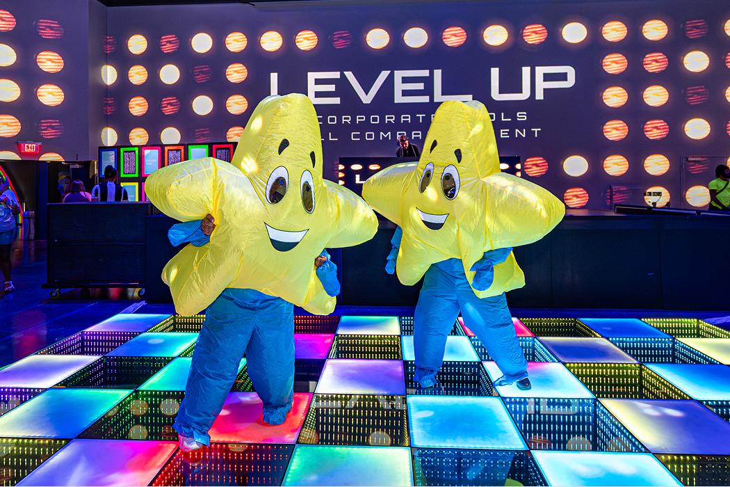 Star mascots posing on a branded dance floor