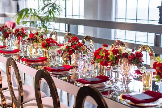 Wedding reception tables with red floral centerpieces and city views