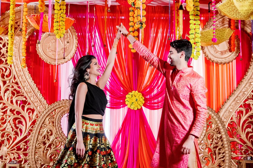 Couple in colorful wedding attire against an ornate red backdrop