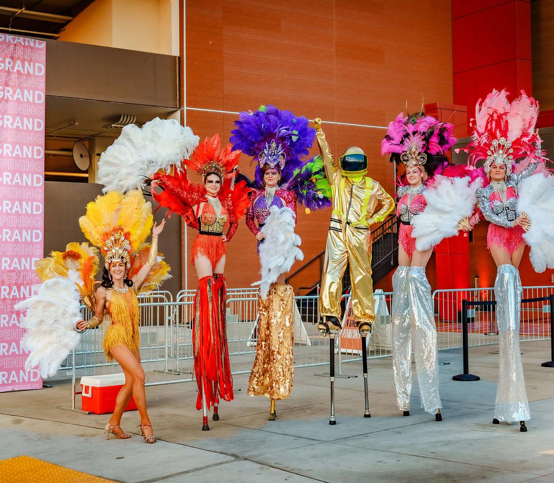 Performers in colorful costumes at a branded activation backdrop