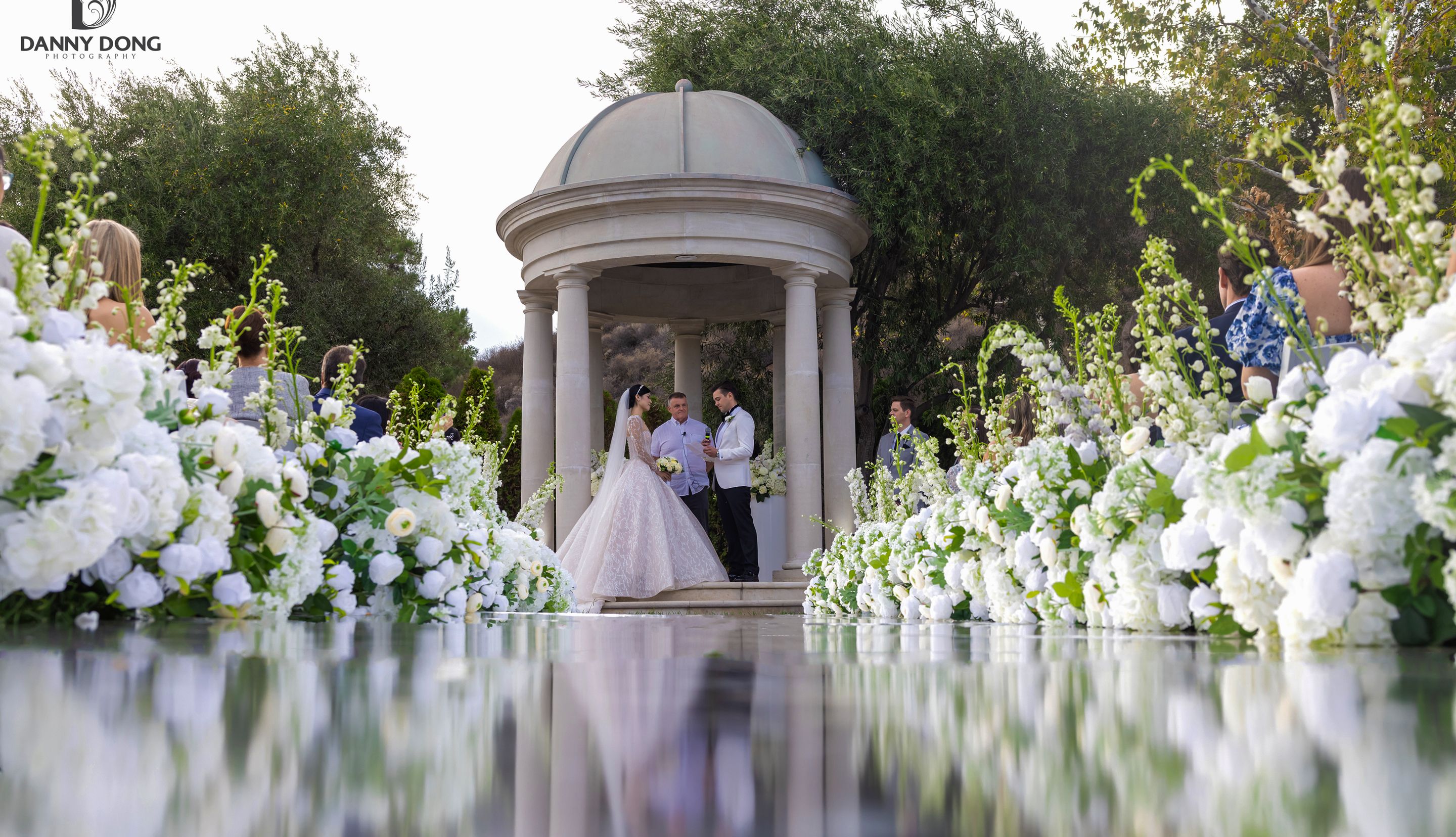 Couple at an outdoor wedding ceremony surrounded by white flowers