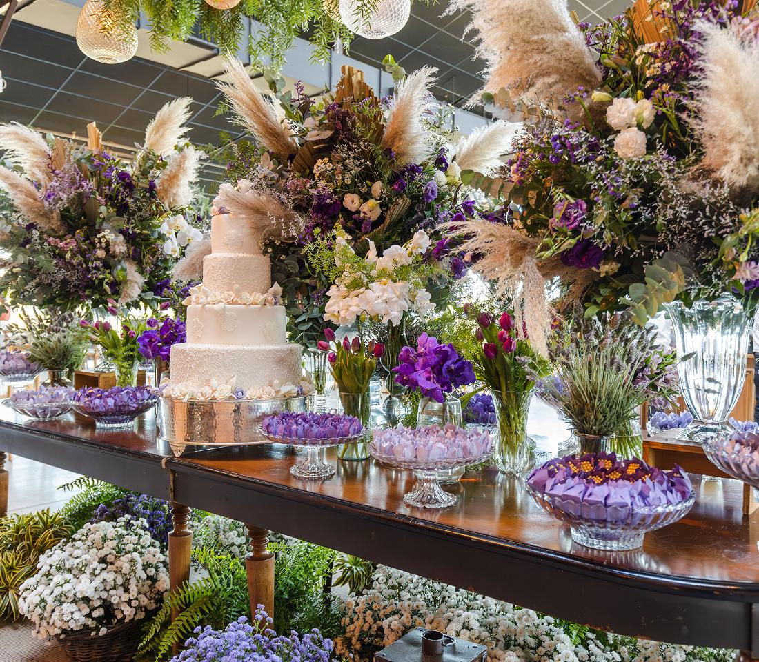Wedding cake surrounded by lush floral arrangements