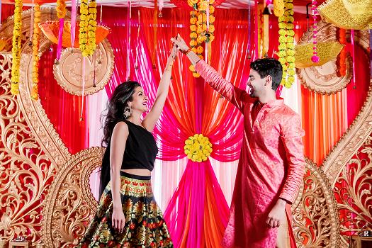 Couple in colorful wedding attire against an ornate red backdrop
