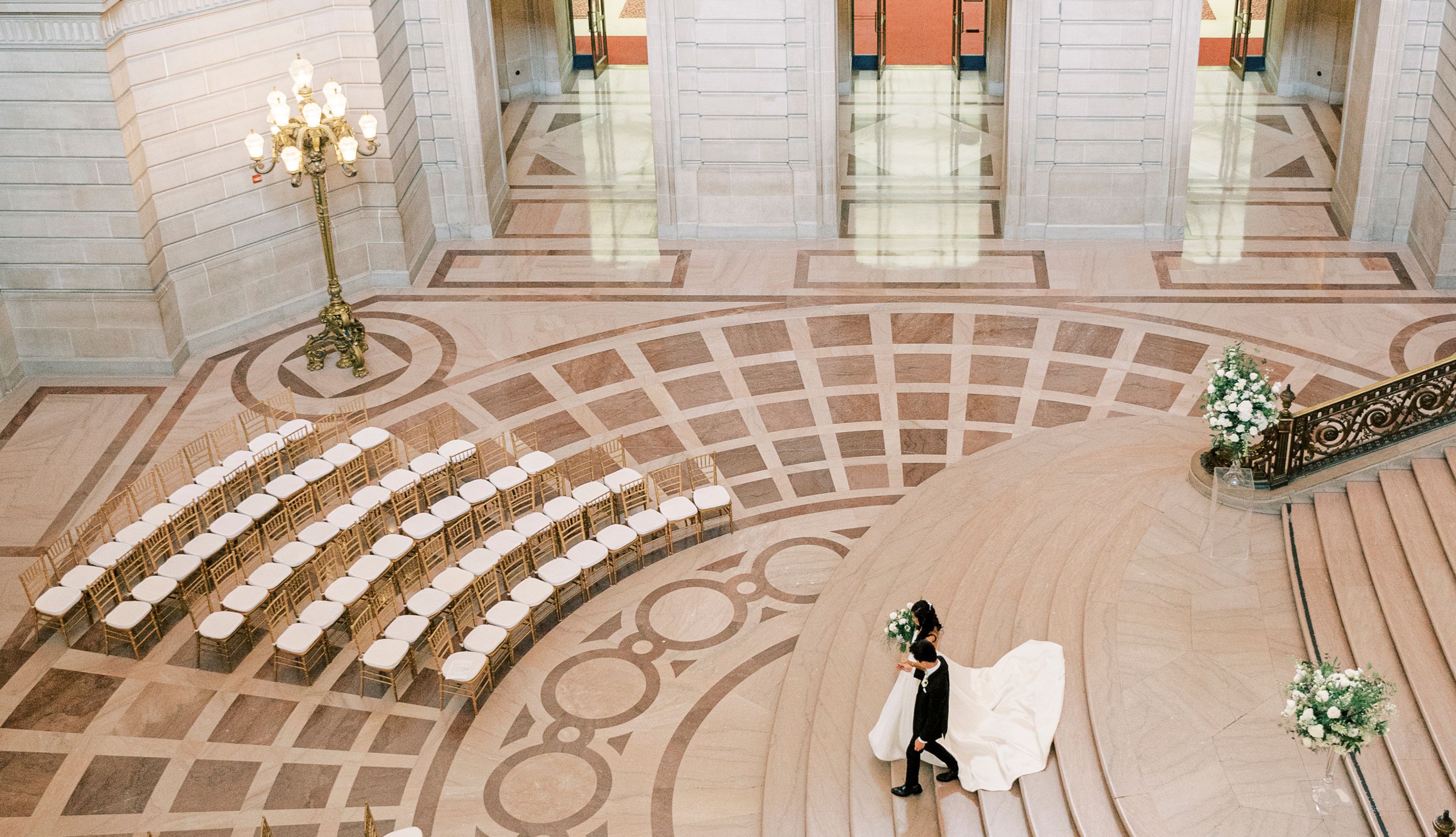 Newlyweds walking through the San Francisco City Hall rotunda