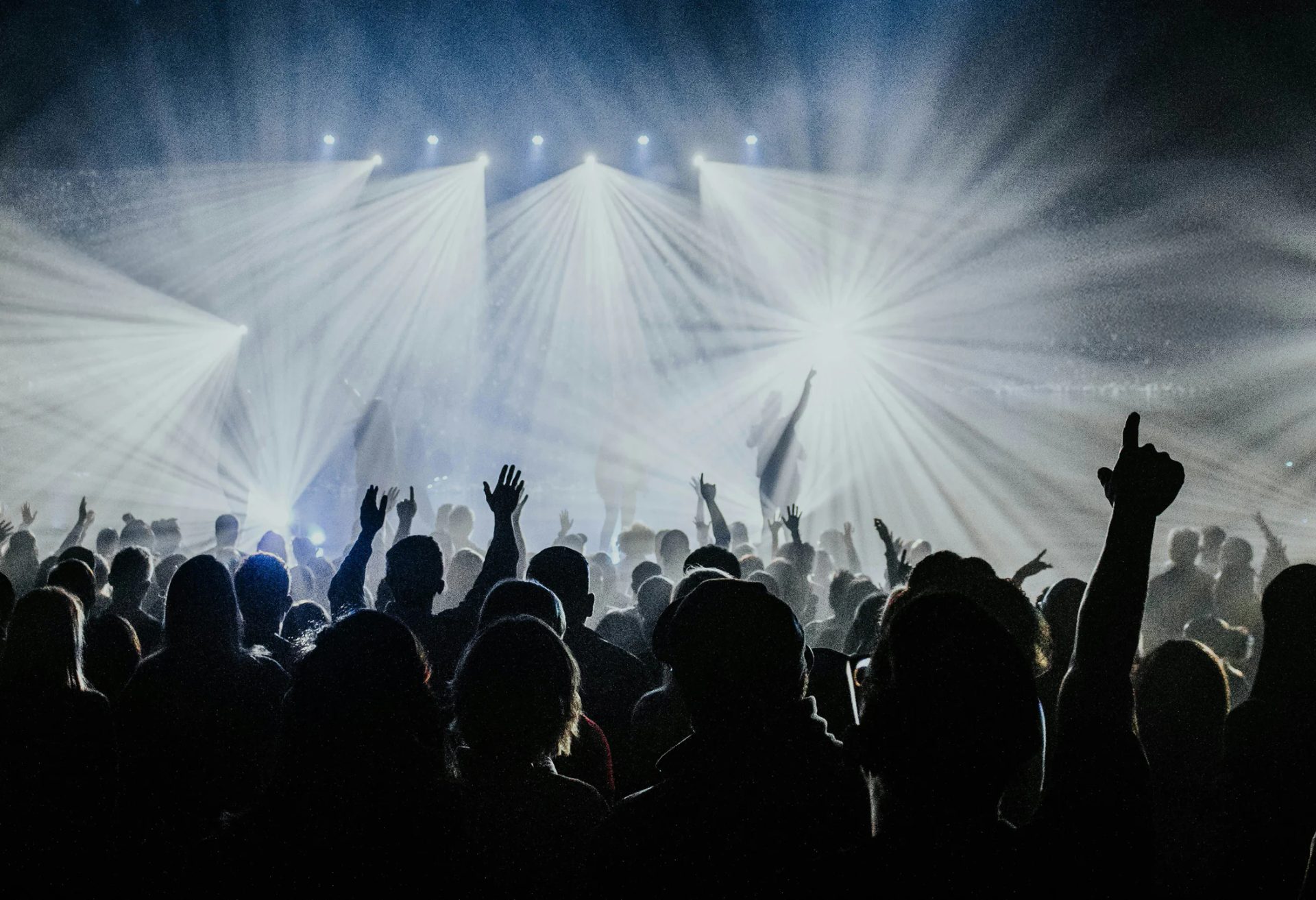 Concert crowd with raised hands and stage lights