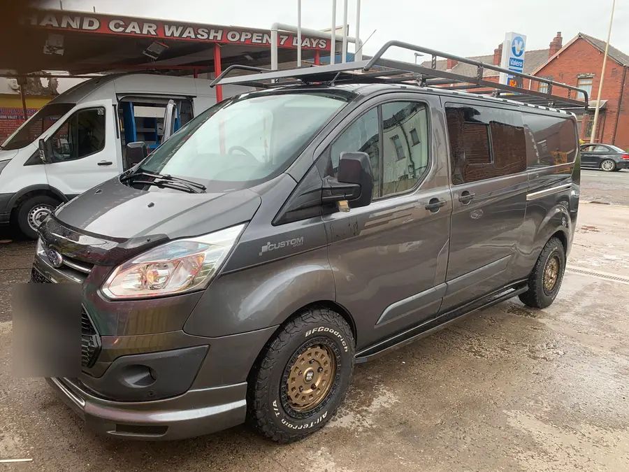 A grey Ford Transit Custom on gold wheels with off-road tyres