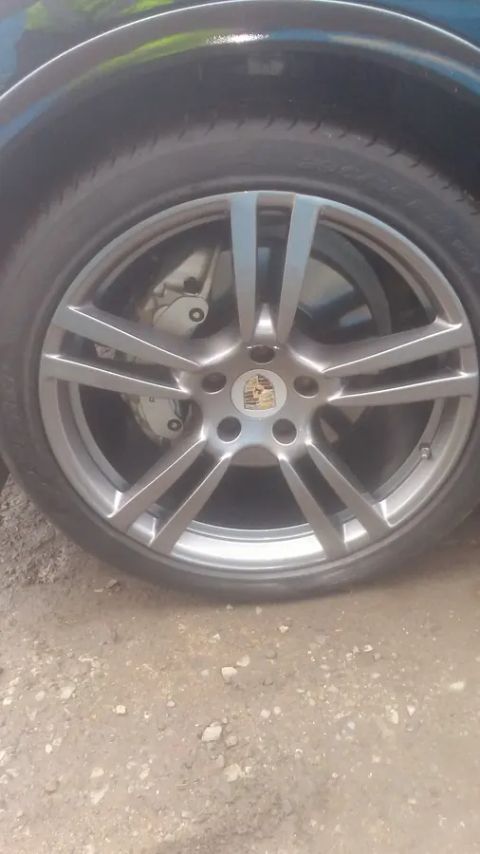 A gunmetal multi-spoke wheel with a Porsche centre cap