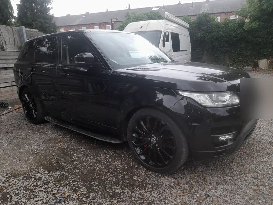 A black Range Rover Sport on gloss black wheels, on the gravel yard