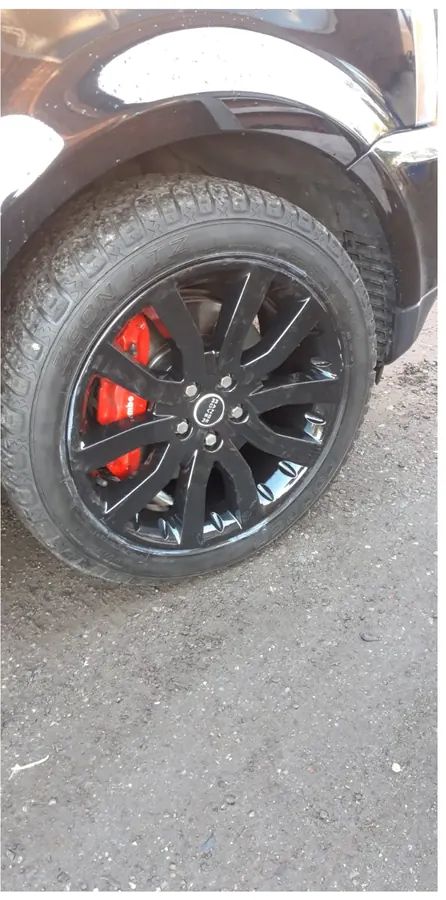 A gloss black Range Rover wheel with a red brake caliper