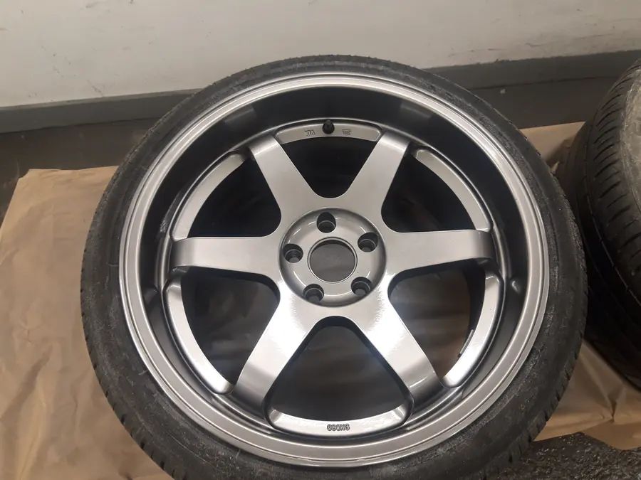 A finished gunmetal six-spoke wheel on masking paper