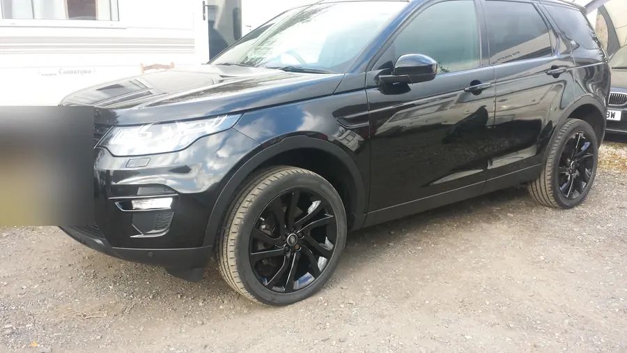 A black Land Rover Discovery Sport on gloss black wheels