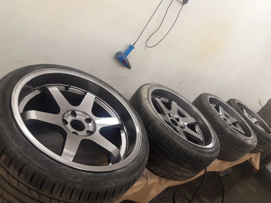 A set of gunmetal six-spoke wheels lined up in the spray booth