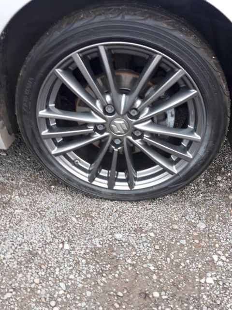 A gunmetal twin-spoke wheel on the gravel yard