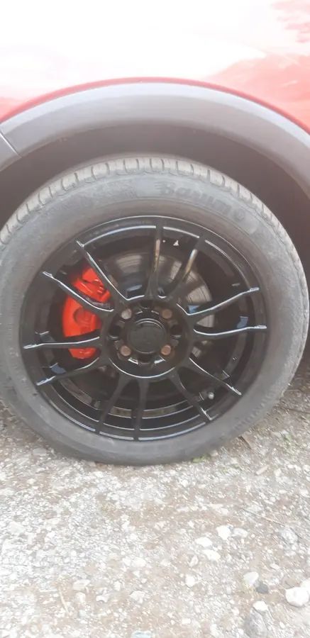 A gloss black wheel with a red brake caliper, on a red van