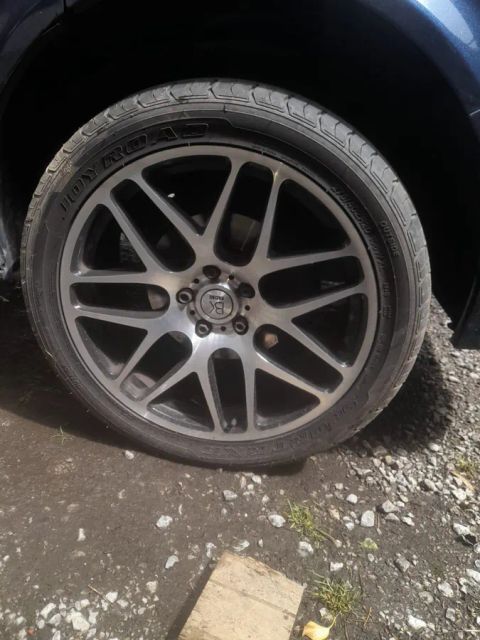 A gunmetal multi-spoke wheel on a dark blue car