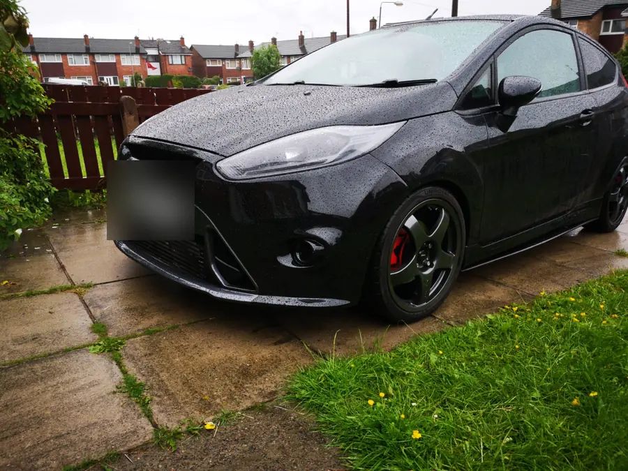 A black Ford Fiesta on gloss black wheels with red brake calipers