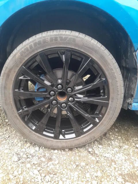 A gloss black multi-spoke wheel on a blue Ford Transit Custom