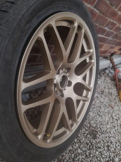 A satin bronze multi-spoke wheel on gravel