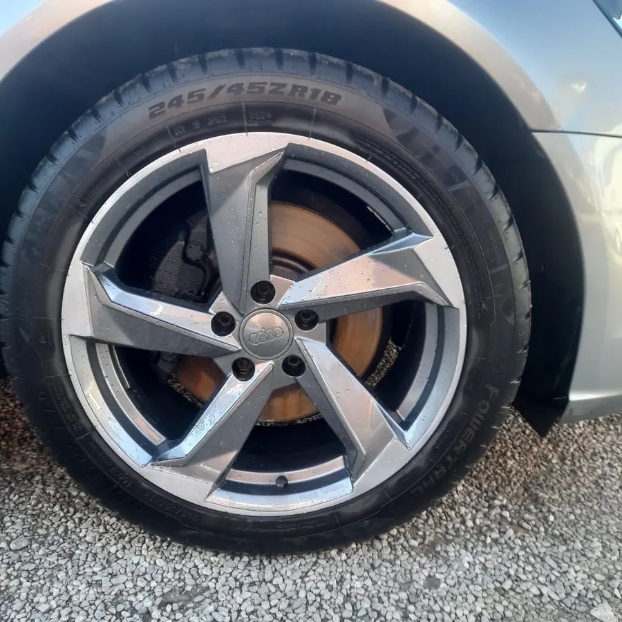 A grey five-spoke wheel on a silver car