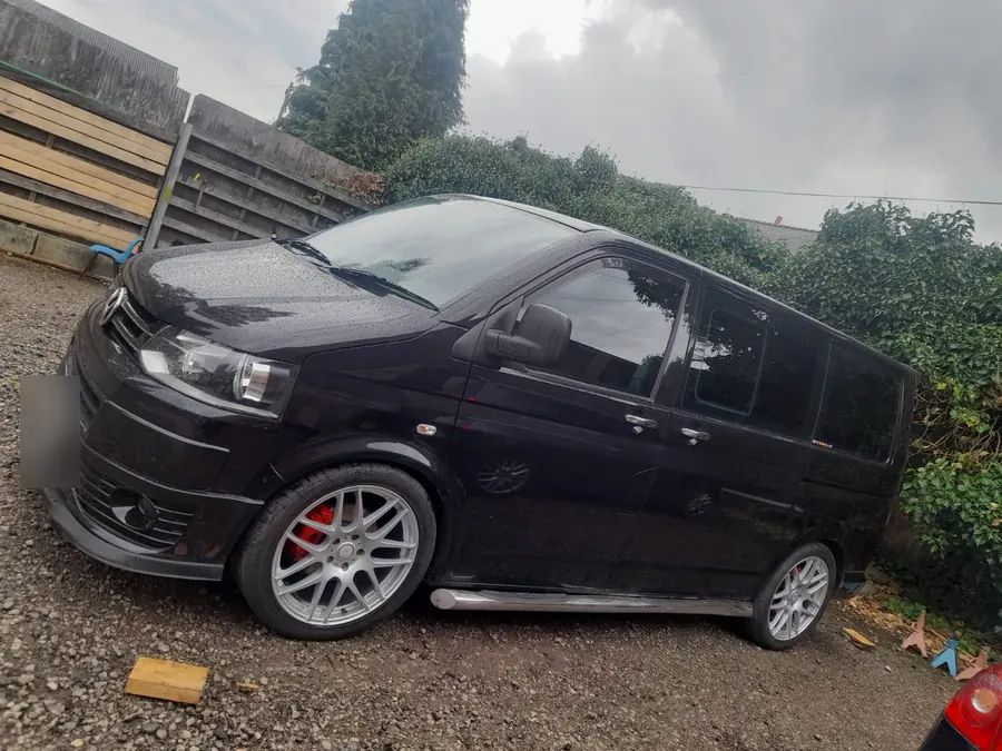 A black van on silver wheels with red brake calipers
