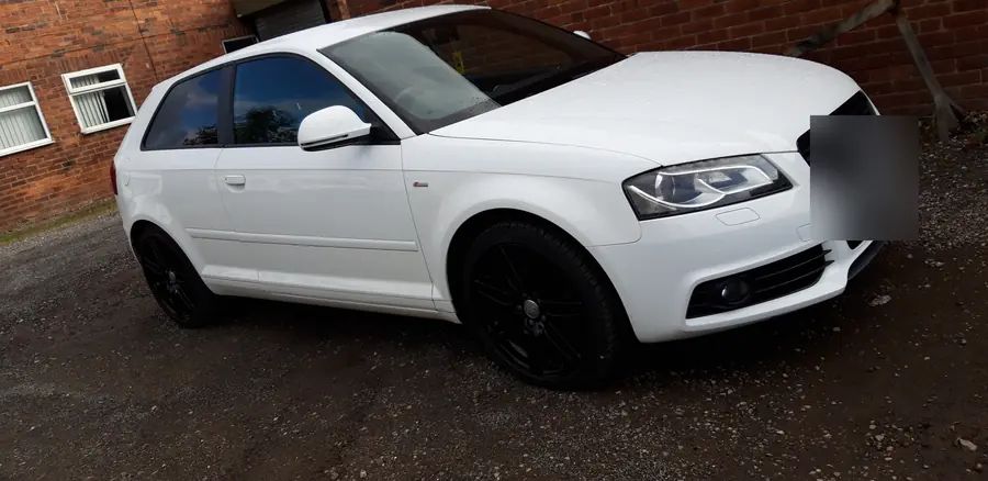 A white Audi A3 on gloss black wheels, against the brick wall