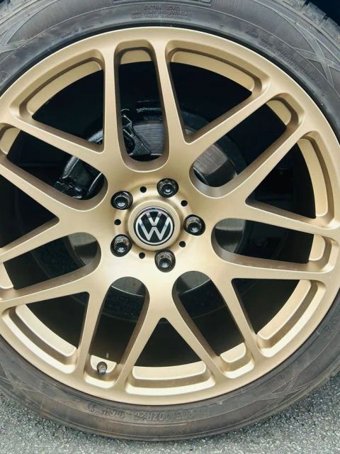 A gold multi-spoke wheel with a VW centre cap