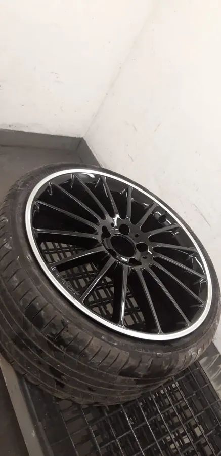 A black wheel with a polished lip, in the spray booth