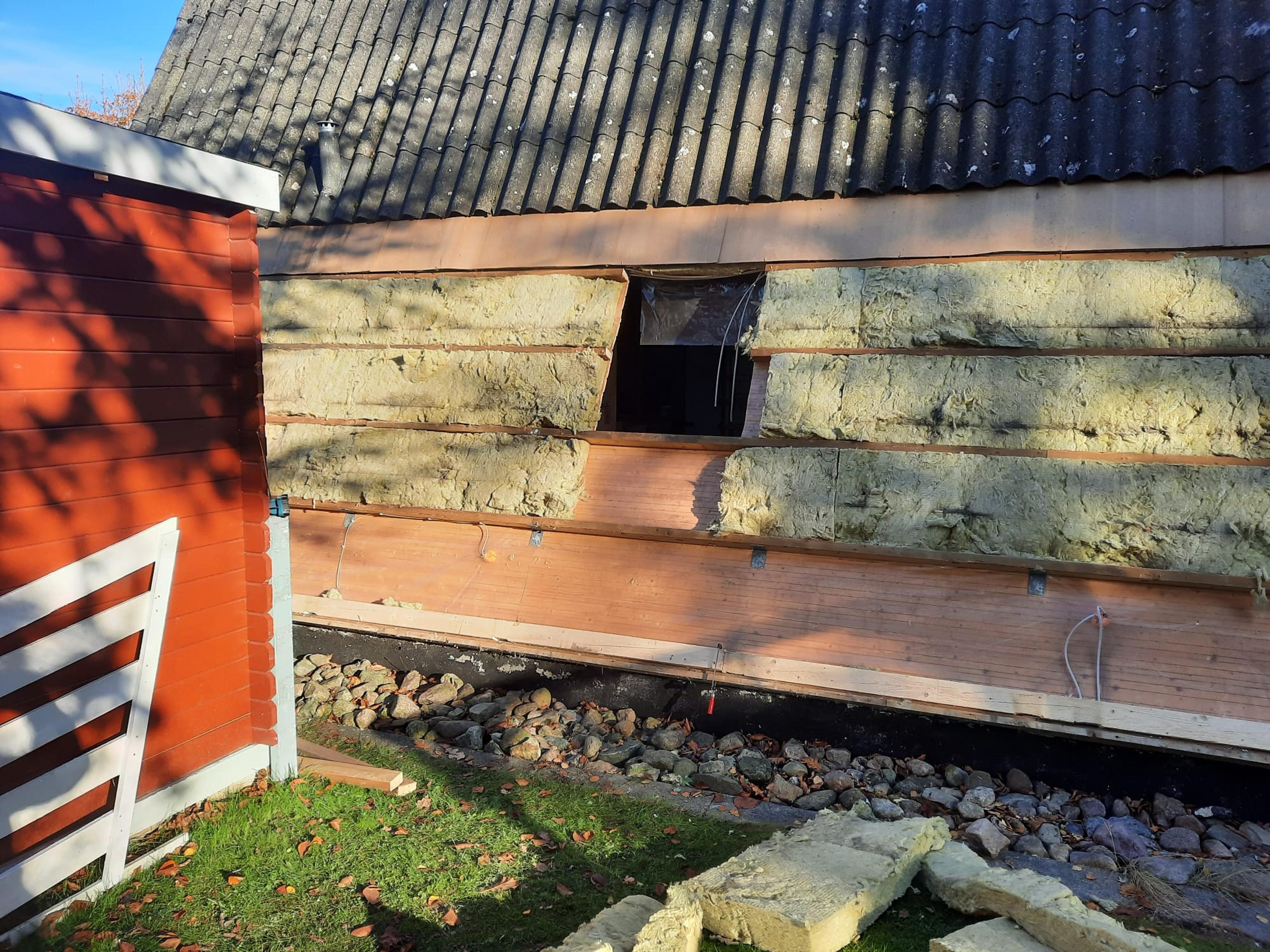 Hauswand mit Dämmmaterialien und Ziegelsteinen im Garten