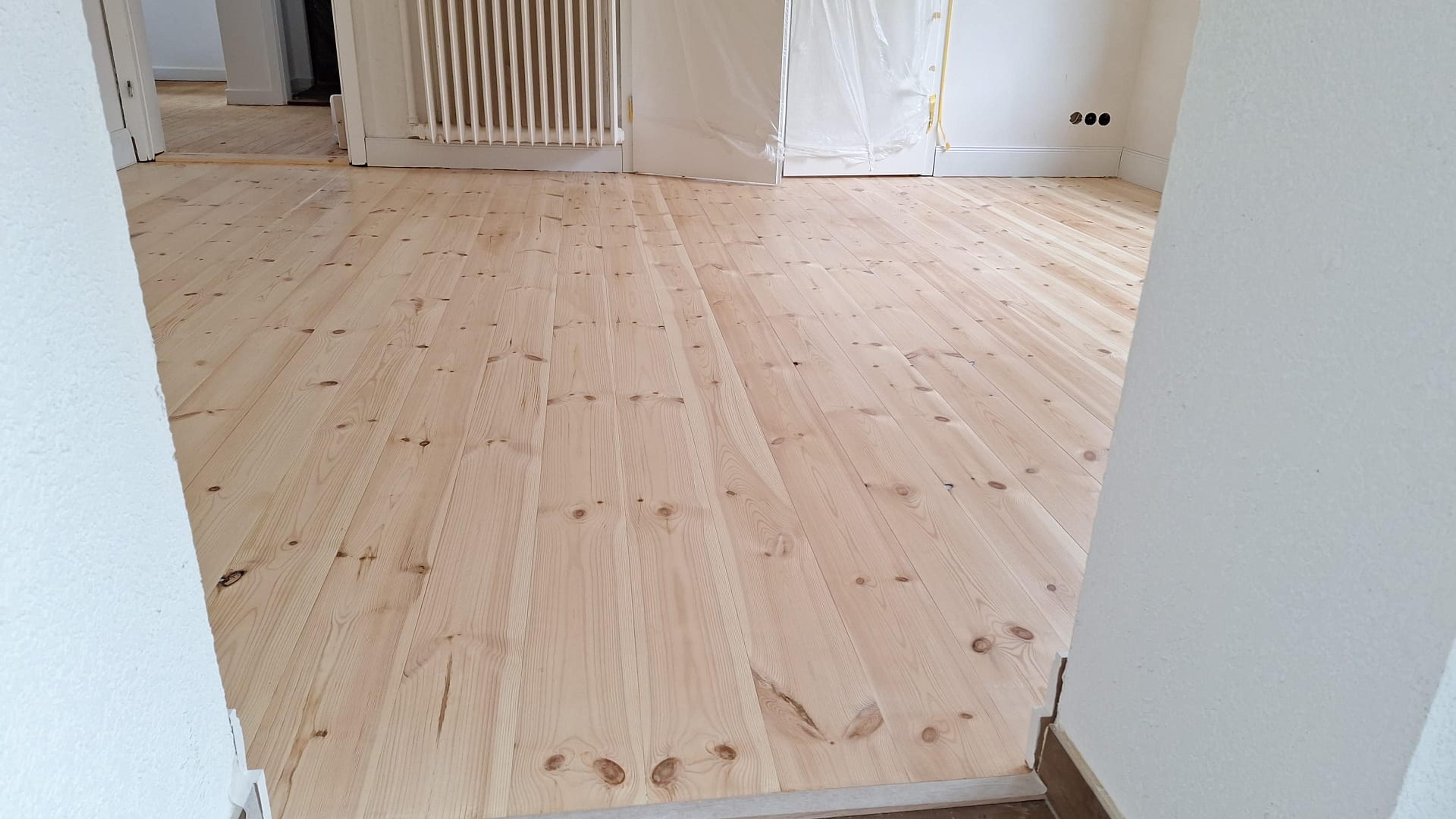 Frisch verlegter, heller Holzboden in einer renovierten Wohnung mit weißen Wänden