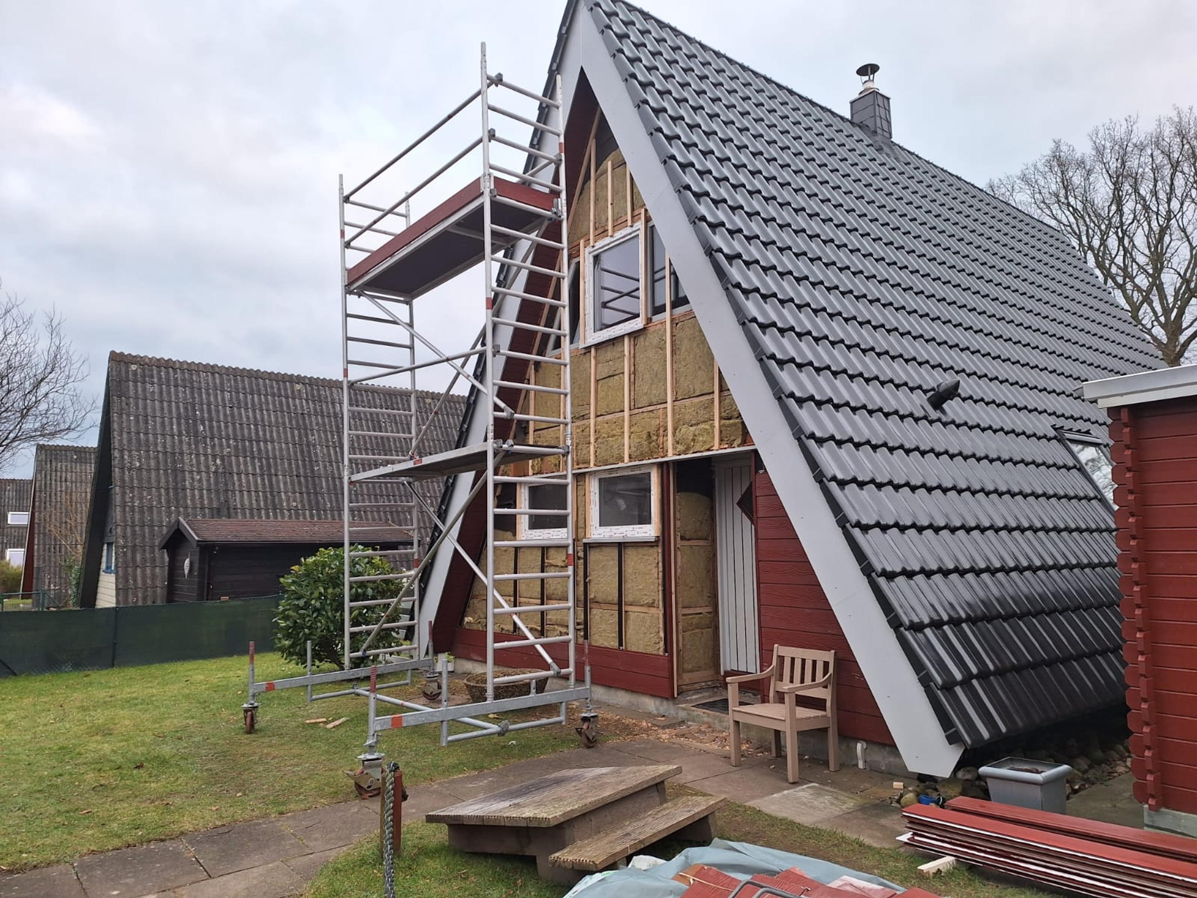 A-Rahmen-Haus mit Baugerüst, teils verdeckter Fassade, graues Dach