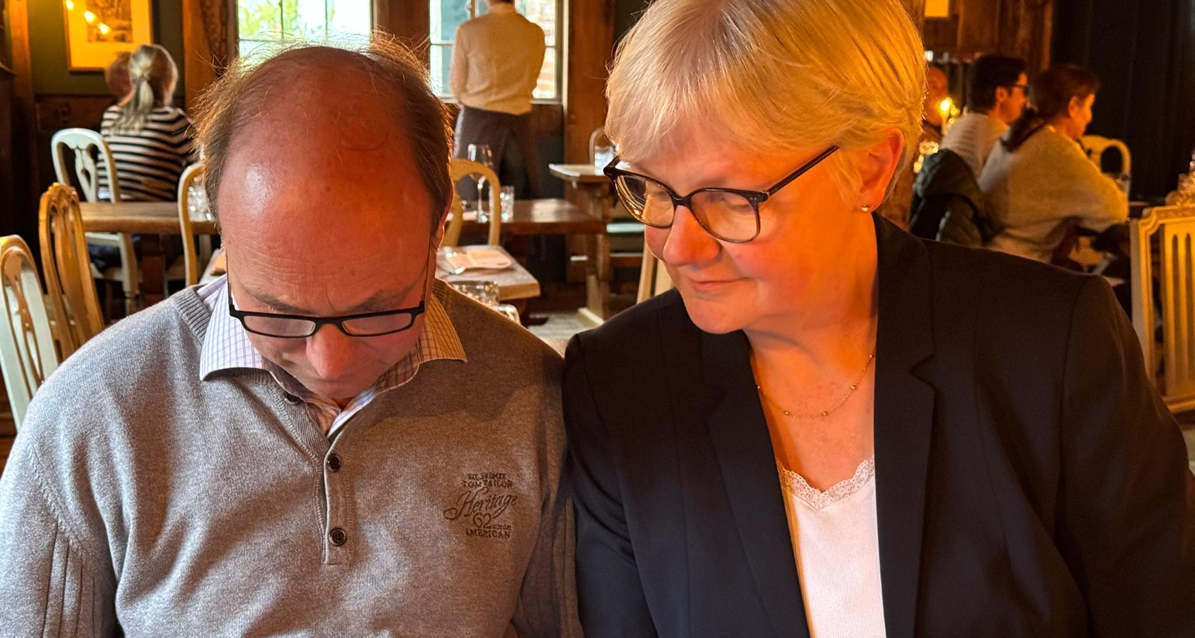 Mann und Frau schauen zusammen in ein Dokument in einem gemütlichen Restaurant